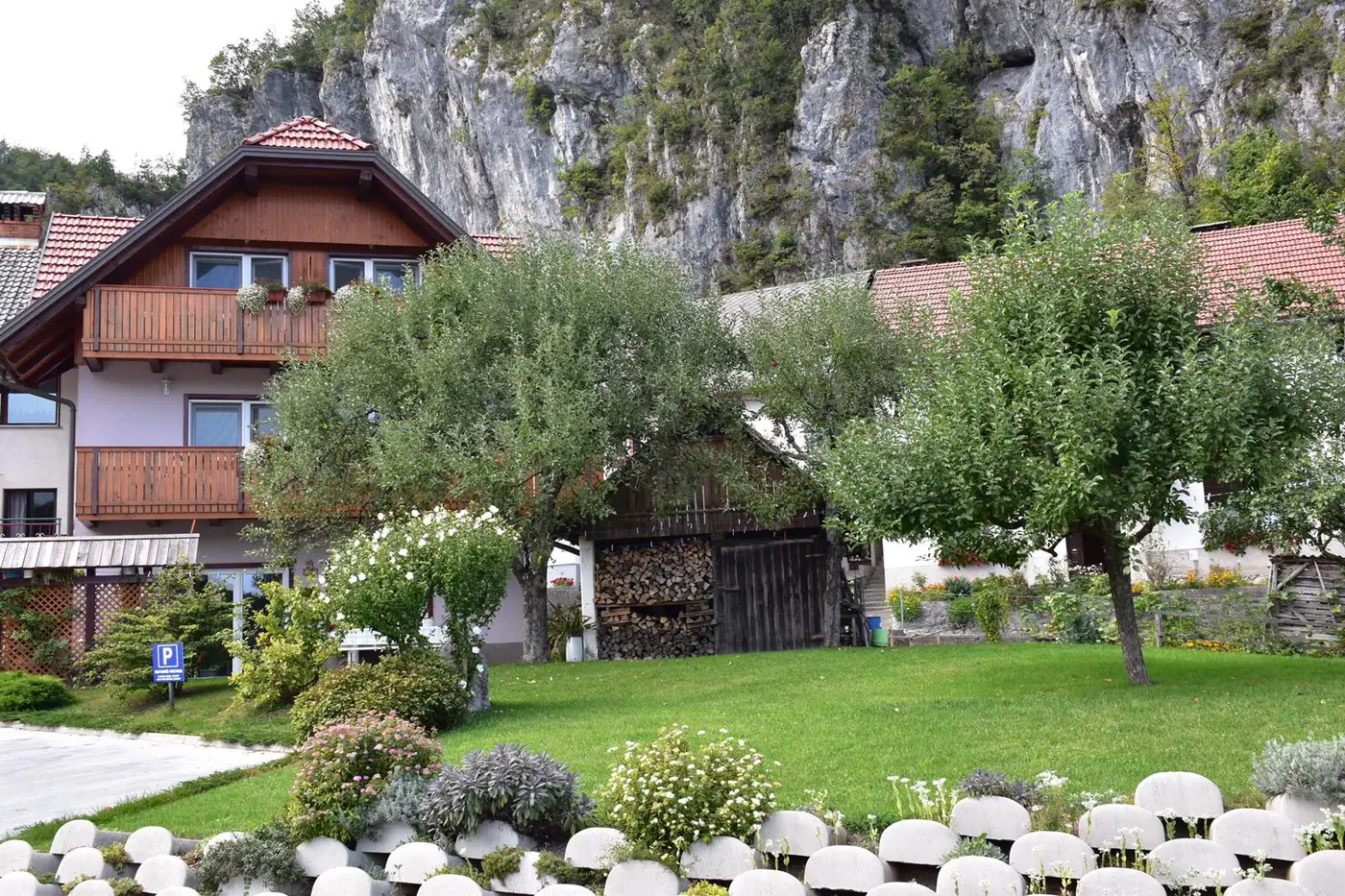 Hiša Sobe Ravnik z lesenimi balkoni, vrtom in jablano pod pečinami v Bohinjski Beli