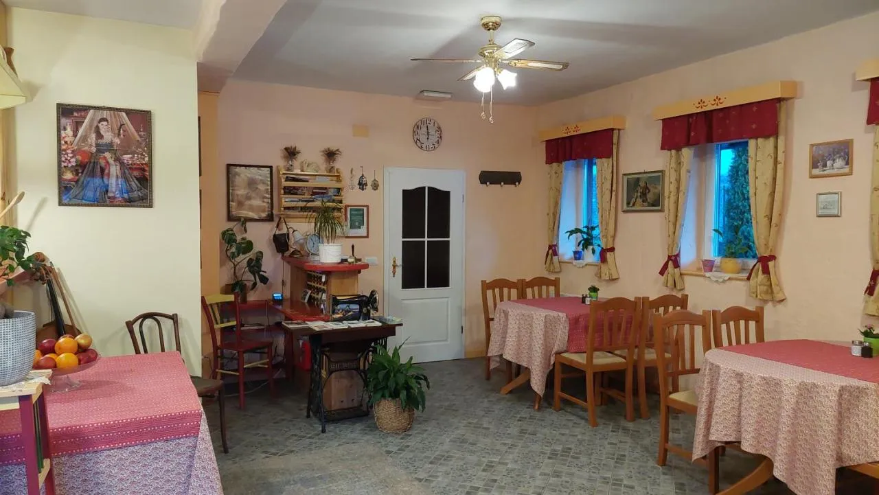 Jedilnica z mizami, pogrnjenimi z rdečimi prti, in starim šivalnim strojem